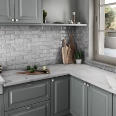 a kitchen with gray cabinets and marble counter tops, along with cutting boards on the sink