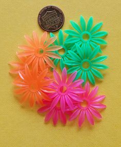 small plastic flowers sitting on top of a yellow table next to a penny for $ 1