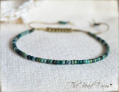 "Dainty Adjustable Yoga Style Anklet -or-  Bracelet with sliding closure. This dainty adjustable piece features colorful tiny 8/0 seed beads in blues and greens with a variety of finishes.   All beads are strung on heavy weight nylon cord in khaki color.  Stacks well with other jewelry pieces or can stand alone.  Perfect for the beach!  So dainty and cute.  So lightweight, you'll never know it's on! Style: ANKLET: opens fully to a 13\" circumference which will slip over the widest part of the foot for most people. After slipping over your foot, pull the tail ends to the desired fit around your ankle. If you feel like you may need a larger circumference, use the reference photo on how to measure the widest part of your foot. If your measurement is larger than 13\", please leave me a note at Green Adjustable Jewelry For Festivals, Green Adjustable Jewelry For Festival, Green Adjustable-length Jewelry For Festival, Green Bracelets With Adjustable Length And Round Beads, Green Bracelets With Adjustable Round Beads, Green Resizable Friendship Bracelets With Round Beads, Green Beaded Bracelets With Adjustable Length, Adjustable Green Hand-strung Friendship Bracelets, Green Adjustable Bracelets For Festivals