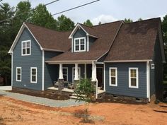 a blue house with white trim on the front and side windows, surrounded by trees