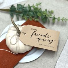 a white pumpkin sitting on top of a plate next to a tag that says happy friends giving