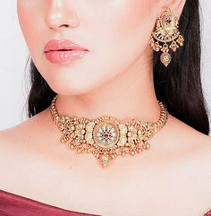 India necklace from Amrapali. This exquisite piece showcases the timeless allure of antique choker designs with a touch of Kundan jewelry elegance. Crafted with precision, it boasts intricate detailing and bears the hallmark of South India's rich jewelry tradition. This gold necklace is a testament to Amrapali's artistry in temple jewelry. Wear it to embody the grace and opulence of India's cultural heritage wherever you go. *𝐏𝐑𝐎𝐃𝐔𝐂𝐓 𝐃𝐄𝐓𝐀𝐈𝐋* * Material: Brass * Plating: Gold Plated 22k Gold Jewelry For Puja, Yellow Gold Kundan Necklace For Diwali, Chandbali Jewelry Sets For Puja, 22k Gold Cutdana Jewelry For Puja, 22k Gold Tilla Jewelry For Navratri, Heavy 22k Gold Jewelry For Navratri, Elegant Zari Work Tikka For Puja, Round Jewelry For Navratri Ceremonial Occasions, Yellow Gold Cutdana Jewelry For Navratri