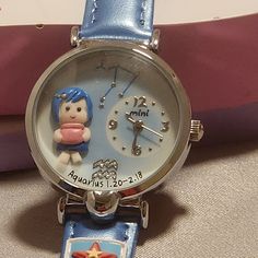 This Mini Brand Handcrafted Watch Is A Unique Timepiece That Features A Zodiac Theme. The Hand Created And Hand Painted Decorations On The Front Of The Watch Features A Character With Blue Hair, They Are Wearing A Blue Dress & Gold Hairclip. They Are Holding A Pink Jar. As With All Of The Zodiac Watches, The Constellation Is Featured With Silver Stars At The Top Of The Face & The Sign Is Shown At The Bottom Of The Face In Crystals Above The Name & Dates Of The Sign. The Watch Has A Round Shape W Artsy Gifts For Friends, Blue Analog Watch Gift, Blue Analog Watch As Gift, Gift Blue Analog Watch, Blue Analog Watch As A Gift, Character With Blue Hair, Cute Figurines, Zodiac Watches, Wishlist Ideas