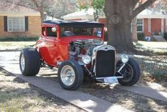 an old model t hot rod car parked on the sidewalk in front of a house