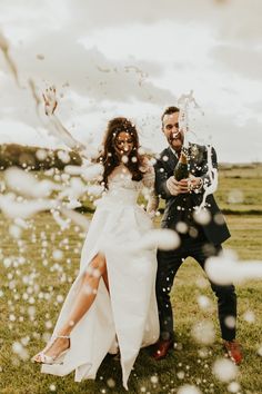 a bride and groom standing in the grass with bubbles coming out of their mouths as they pose for a photo