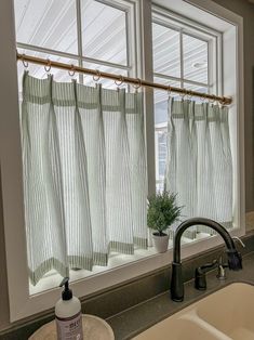 a kitchen sink with a faucet next to a window covered in green curtains