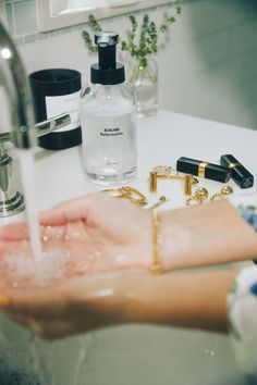 a person is washing their hands with soap and other personal care items on the sink