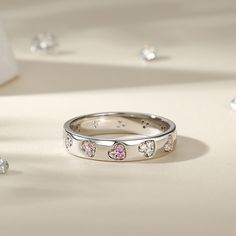 This sterling silver women's band radiates with the warmth and depth of love. Adorned with hearts of varying hues. Wrap your finger in the whimsical sparkle of this heart ring. The ring is expertly crafted from durable and shining sterling silver that features heart inlaid by multi-colored stones to add a sparkling texture to your look. It glimmers in the light, catching the eye with its simple yet striking design. The hearts are carefully set into the band, creating a harmonious and eye-catchin Valentine's Day Round Band Promise Jewelry, Silver Cubic Zirconia Heart Ring For Mother's Day, Fine Jewelry Round Band For Valentine's Day, Pink Sterling Silver Heart Ring For Promise, Silver Round Band Jewelry For Valentine's Day, Stackable White Gold Jewelry For Valentine's Day, Fine Jewelry For Valentine's Day, Valentine's Day 925 Stamped Heart Ring, Valentine's Day Stackable White Gold Jewelry