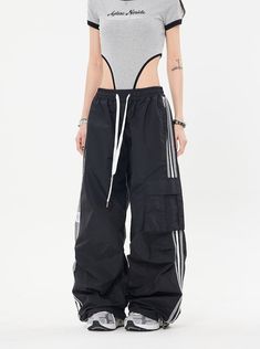 Our Striped Wide Leg Track Pants combine classic style with a relaxed fit for effortless comfort. Made with an elastic drawstring waistband and a striped pattern, these pants are perfect for weekend lounging at home or a casual day out. Model is 5'2 100lbs wearing M Techwear Design, Grunge Outfits Black, Streetwear Techwear, 90s Fashion Grunge Outfits, Baggy Track Pants, Iconic Y2k, Wide Leg Joggers, Junior Pants, Cargo Sweatpants