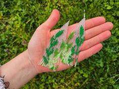 a hand is holding some beads in it's palm with green leaves on them