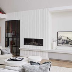 a living room with white furniture and paintings on the wall above it's fireplace