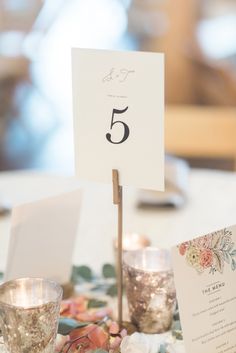 the table is set with silver cups and place cards