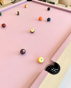 a pink pool table with several balls on it