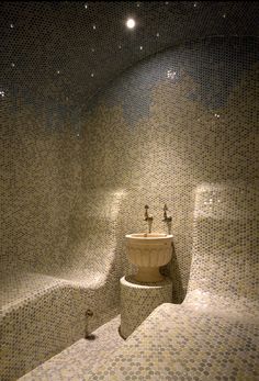 a bathroom with mosaic tile walls and a toilet next to a bidet in the corner