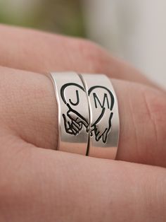 someone is holding their wedding ring with the initials m and c on it's side