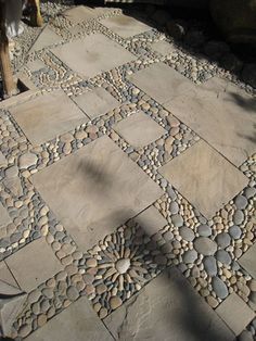 an outdoor patio with stone tiles in the shape of squares and circles on top of it