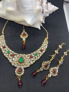 Red and green kundan set This is an elegant piece of jewelry and it's a green and red colour kundan set. This set can be worn as a choker.  This set comes with a necklace, a pair of earrings and a maang tikka(forehead piece). Red Kundan Necklace With Stone Work, Red Kundan Temple Jewelry Set, Red Kundan Necklace With Stone Work Bollywood Style, Bollywood Style Red Kundan Necklace With Stone Work, Red Kundan Jewelry Set Gift, Red Kundan Jewelry Sets With Stone Work, Red Kundan Necklace With Meenakari, Red Kundan Sets For Gift, Red Kundan Choker With Stone Work