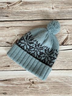 a gray and black knitted hat sitting on top of a wooden floor