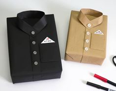 a black shirt and scissors are next to a brown box with white writing on it