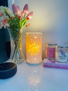 a vase with flowers and candles sitting on a table next to a candle holder that has an image of the sun in it