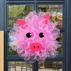 a pink pig wreath hanging on the front door of a building with black glass doors