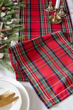 the table is set for christmas dinner with red and green plaid napkins