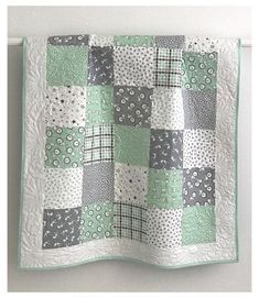 a green and white quilt hanging on the wall