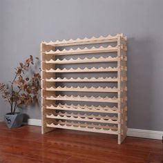 a wooden wine rack sitting on top of a hard wood floor next to a potted plant