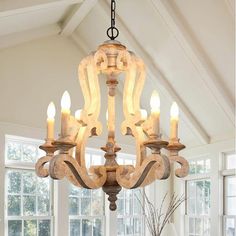 a chandelier hanging from the ceiling in a room with large windows and white walls