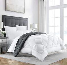 a bed with white and black comforters in a bedroom next to a window,