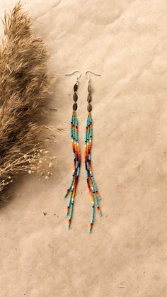 a pair of earrings sitting on top of a sandy beach