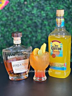 three different types of alcohol sitting on a table next to each other with lemon wedges