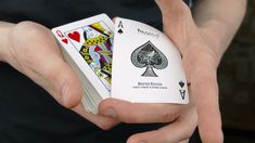 a person holding two playing cards in their hands