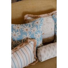 four pillows on a couch with palm trees in the back and blue stripes down the middle