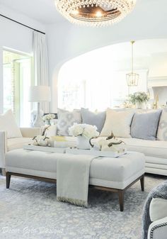 a living room filled with furniture and a chandelier hanging from the ceiling above