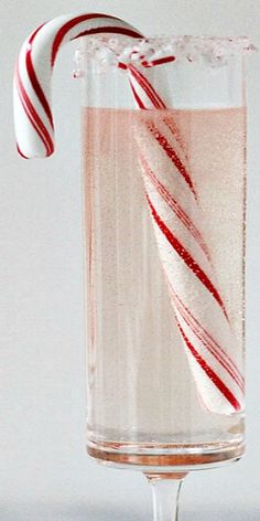 a candy cane sticking out of a glass filled with liquid