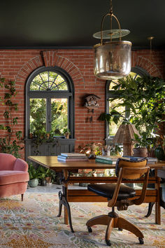 a living room filled with furniture and a large window covered in plants next to a brick wall