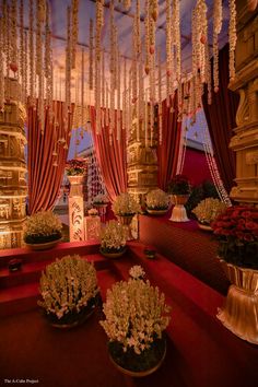 an elaborately decorated room with red curtains and flowers in vases on the floor