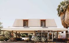 the front of a building with palm trees