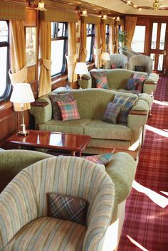 there are many couches and chairs in this train car that is decorated with plaid fabric