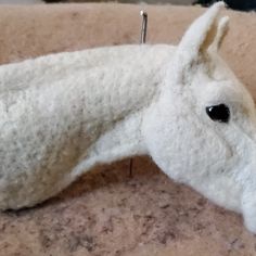 a close up of a white horse head on a table with pins in its mouth