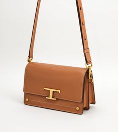 Bag in elegant leather with a Tod's T Timeless metal accessory, branded rivets, and an adjustable and removable handle. Tods Bag, Cross Body Bags, Brown Shoulder Bag, Shoulder Bags For Women, Metal Accessories, Online Bags, Rivets, Kate Spade Crossbody, Leather Crossbody Bag