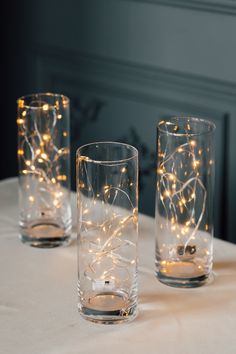 three glasses with lights in them sitting on a table