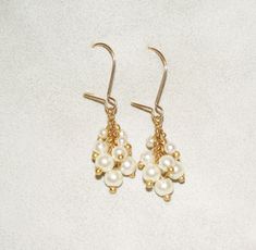 "A beautiful cluster pearl dangle earrings. These delicate dangle bridal earrings are both a timeless classic and modern Boho-chic. The earrings are made from cream Swarovski pearls with a hanging hook earring, The beads are connected loosely and individually, in a delicate cluster beadwork that allows them to move, and grants them a grape line look. This design is available with a hook or with a post - the hook can be replaced with a stud pearl earrings. These vintage-inspired earrings are made White Pearl Drop Dangle Cluster Earrings, White Pearl Drop Cluster Earrings, White Pearl Drop Cluster Earrings For Anniversary, Wedding Cluster Dangle Earrings With Pearl Drop, Wedding Pearl Drop Cluster Earrings, Wedding Cluster Earrings With Pearl Drop, Pearl Drop Cluster Earrings For Anniversary, Anniversary Pearl Drop Cluster Earrings, Dangle Pearl Drop Cluster Earrings