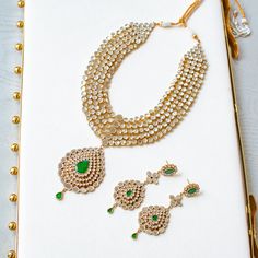 An heirloom of divinity, crafted through the ages! Introducing an opulent fiver-layer kundan mala, adorned with a magnificent emerald stone centerpiece that exudes timeless elegance, this set blends the regal charm of kundan with the vibrant allure of emeralds. A masterpiece of craftsmanship, it promises to elevate any occasion with its majestic allure. The listing includes long mala and a pair of matching earrings. Please click on the video for a detailed view of the product. Gold-plated on hig Emerald Kundan Necklace With Intricate Design For Festive Occasions, Festive Emerald Kundan Necklace With Intricate Design, Festive Emerald Kundan Chandbali Necklace, Festive Chandbali Kundan Necklace With Emerald, Festive Emerald Kundan Necklace With Stone Work, Green Chandbali Bridal Necklace For Rituals, Festive Emerald Jewelry Sets With Stone Work, Jeweled Kundan Necklace For Rituals, Green Kundan Necklace For Rituals In Temple Style