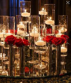 candles and roses are arranged on a glass table in front of a chandelier