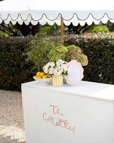 an ice cream stand with flowers and lemons on the table under a white umbrella