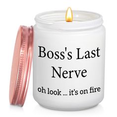 a white candle with a pink lid that says boss's last nerve oh look it's on fire