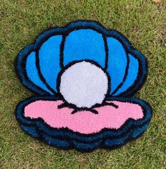 a close up of a rug on the ground with a blue and pink shell design