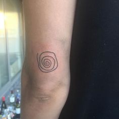 a person with a small tattoo on their arm that has an image of a spiral